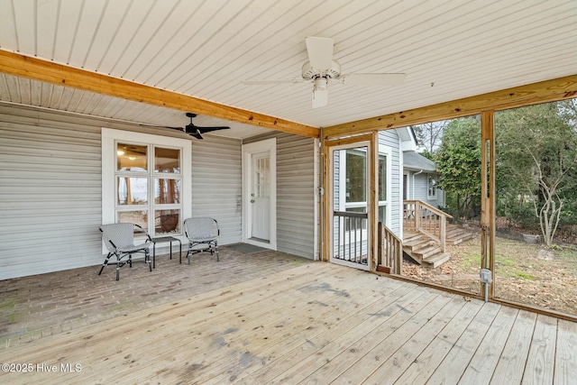 unfurnished sunroom featuring plenty of natural light, beamed ceiling, and ceiling fan