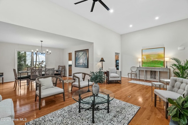 living room featuring ceiling fan with notable chandelier and light hardwood / wood-style flooring