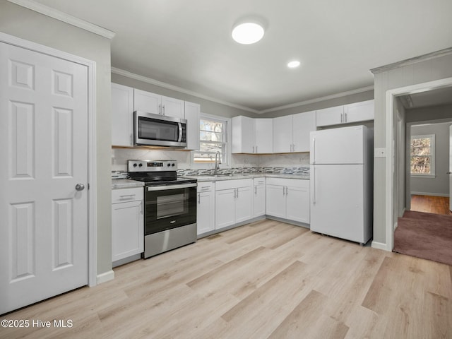 kitchen with white cabinetry, sink, ornamental molding, and stainless steel appliances