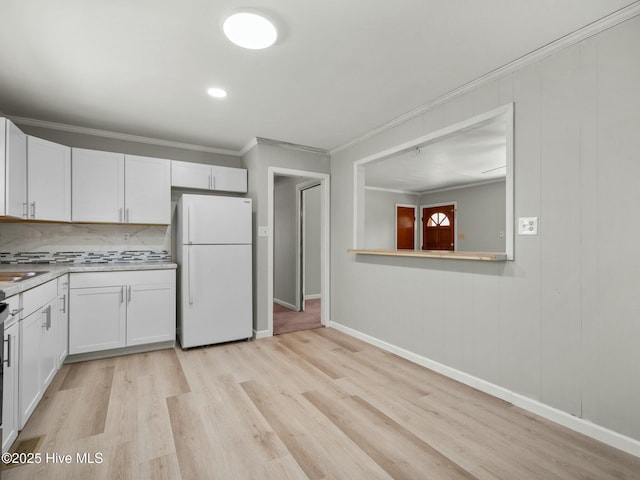 kitchen with white cabinetry, crown molding, tasteful backsplash, light hardwood / wood-style flooring, and white refrigerator