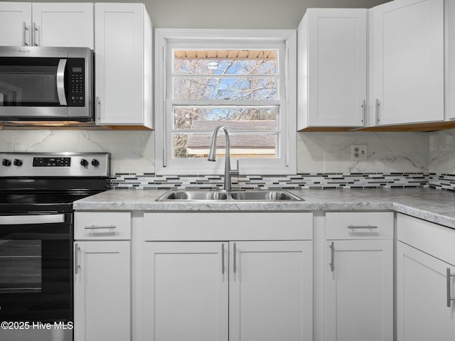 kitchen with white cabinetry, appliances with stainless steel finishes, sink, and backsplash