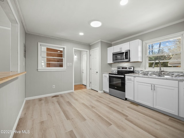 kitchen featuring sink, white cabinets, stainless steel appliances, crown molding, and light hardwood / wood-style flooring