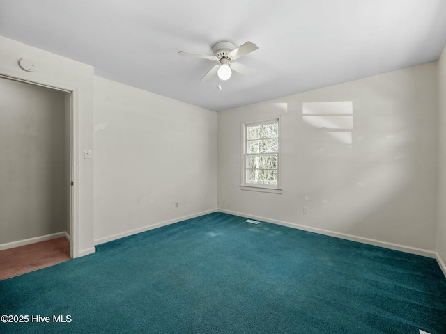 spare room featuring ceiling fan and dark carpet