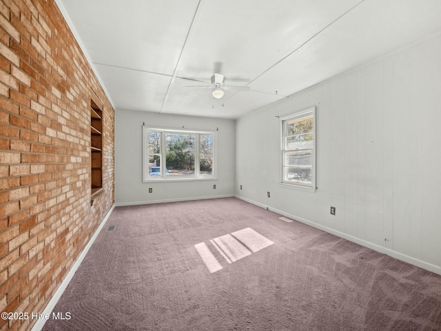 carpeted empty room featuring built in features, ceiling fan, and brick wall