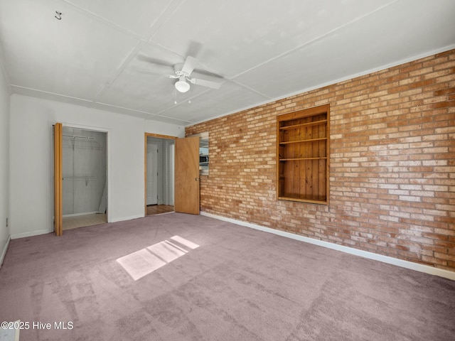 unfurnished bedroom with carpet floors, ceiling fan, and brick wall