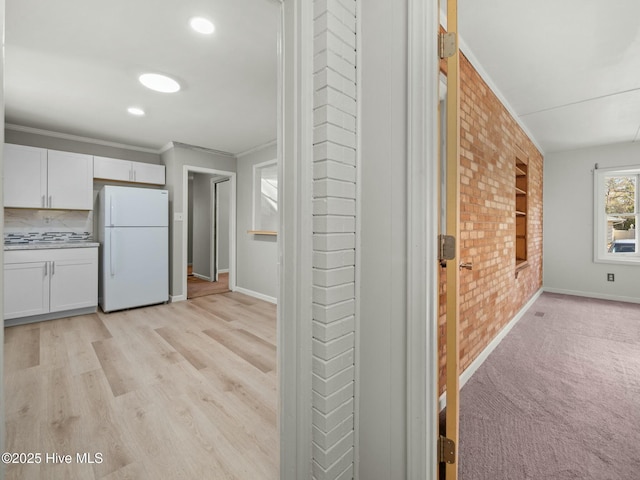 interior space featuring ornamental molding, light hardwood / wood-style floors, and brick wall