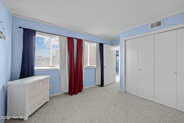 unfurnished bedroom with light colored carpet, a closet, and a textured ceiling