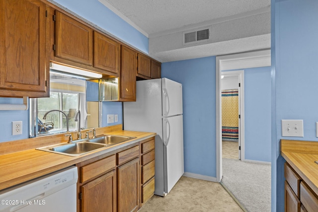 kitchen featuring light carpet, white appliances, sink, and a textured ceiling