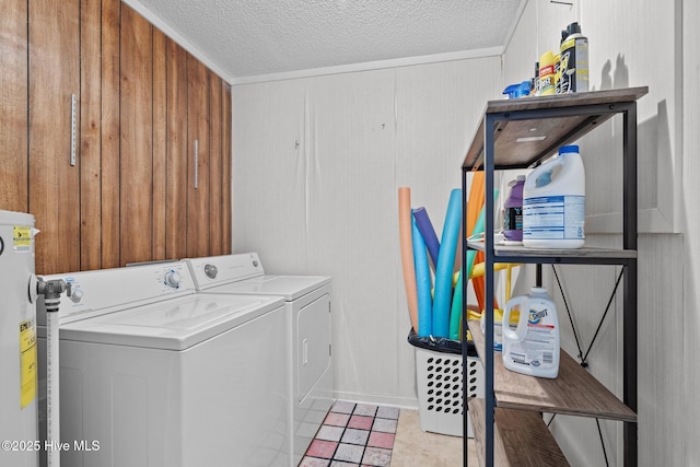 laundry room featuring wooden walls, washer and clothes dryer, water heater, and a textured ceiling