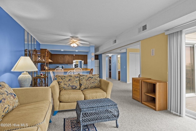 living room featuring a textured ceiling, light colored carpet, and ceiling fan