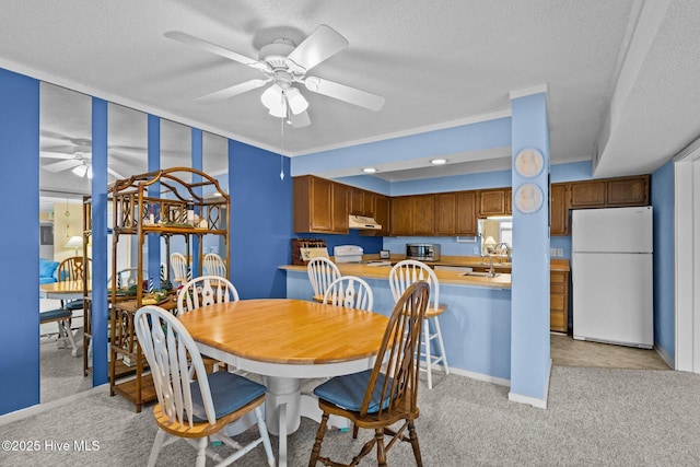 carpeted dining space with ceiling fan, sink, and a textured ceiling