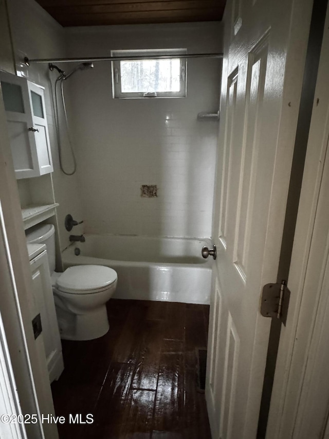 bathroom featuring hardwood / wood-style flooring, tiled shower / bath combo, and toilet