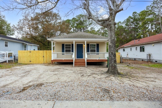 view of front facade with a porch, a gate, roof with shingles, and fence