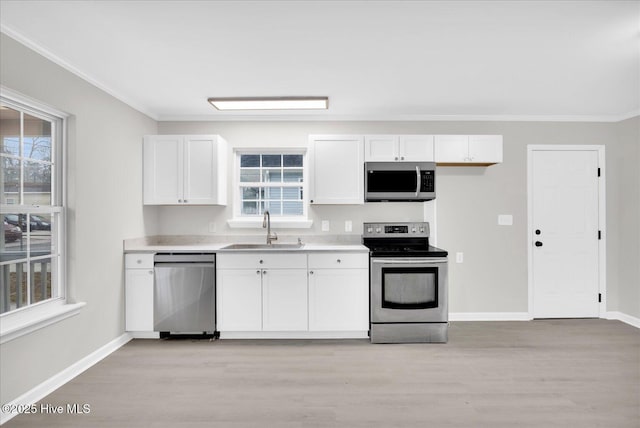 kitchen with light countertops, appliances with stainless steel finishes, a sink, and white cabinetry