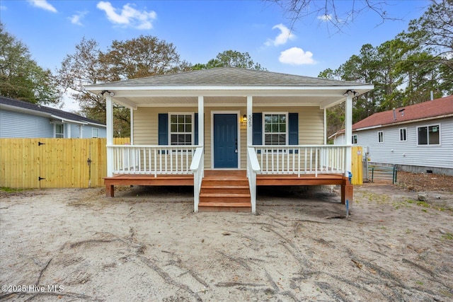 view of front of home with a porch, a shingled roof, and fence