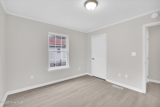 empty room featuring baseboards, crown molding, visible vents, and light wood-style floors