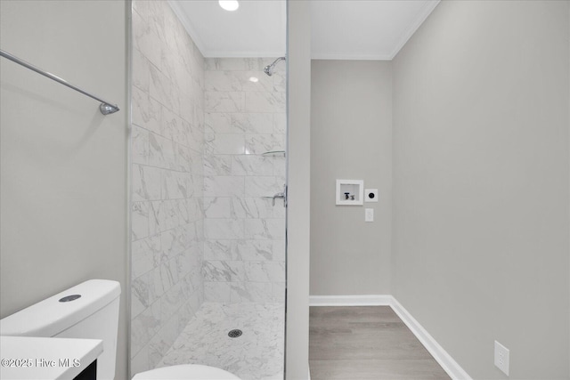 full bathroom with baseboards, toilet, a tile shower, crown molding, and vanity