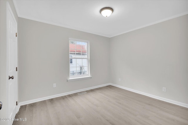 unfurnished room with light wood-type flooring, baseboards, visible vents, and ornamental molding