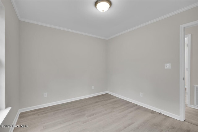 empty room with light wood-style floors, visible vents, ornamental molding, and baseboards