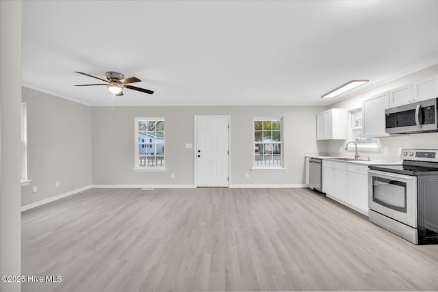 kitchen with a sink, white cabinetry, open floor plan, light countertops, and appliances with stainless steel finishes