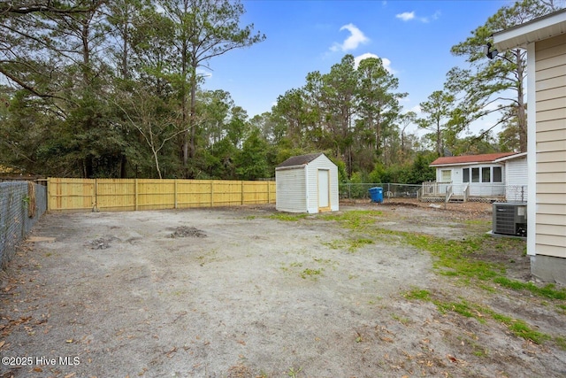 view of yard featuring a storage shed, central AC unit, an outbuilding, and a fenced backyard