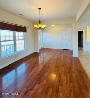 unfurnished dining area with a notable chandelier and dark hardwood / wood-style floors