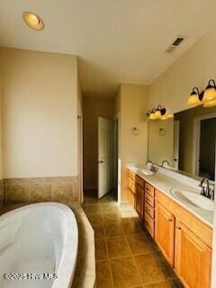 bathroom with tile patterned floors, vanity, and tiled tub