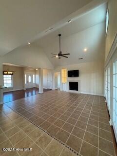 unfurnished living room with dark tile patterned floors, high vaulted ceiling, and ceiling fan