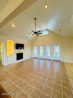 unfurnished living room with tile patterned flooring, high vaulted ceiling, built in features, and ceiling fan