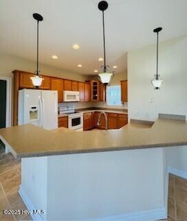 kitchen featuring hanging light fixtures, white appliances, and light tile patterned floors