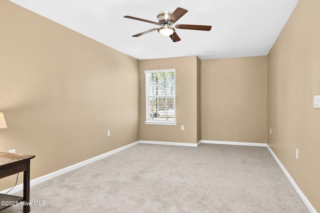 carpeted spare room with ceiling fan and baseboards