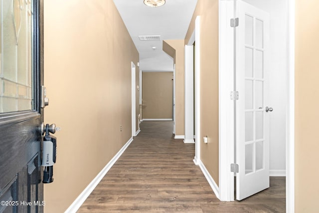 corridor featuring wood finished floors, visible vents, and baseboards