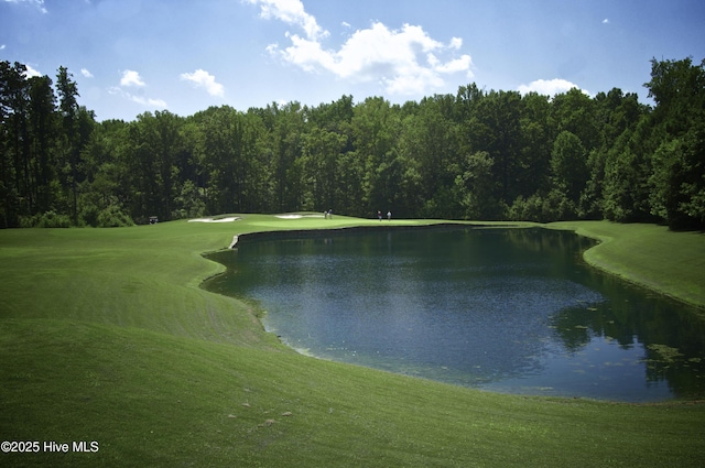 view of property's community featuring a wooded view, a water view, a lawn, and golf course view