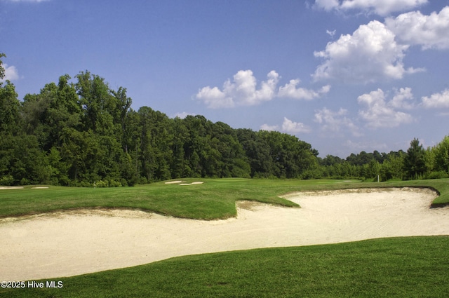 view of community with a lawn, a view of trees, and golf course view