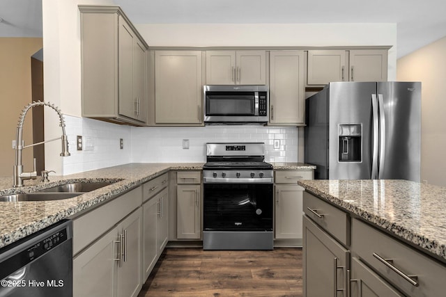 kitchen featuring decorative backsplash, appliances with stainless steel finishes, dark wood-type flooring, gray cabinets, and a sink