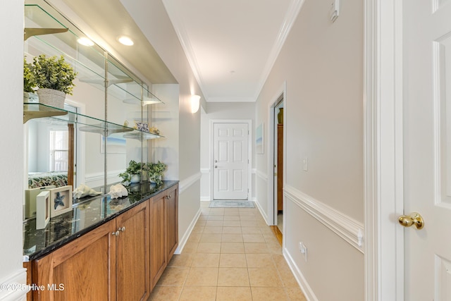 bar featuring light tile patterned flooring, crown molding, and dark stone counters