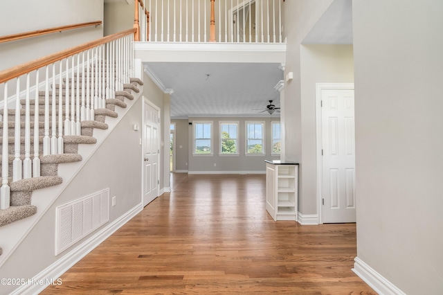 foyer featuring wood-type flooring, ceiling fan, and a high ceiling