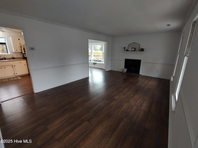 unfurnished living room with dark hardwood / wood-style flooring, crown molding, and plenty of natural light