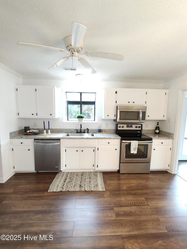 kitchen featuring white cabinetry, appliances with stainless steel finishes, crown molding, and dark wood-type flooring