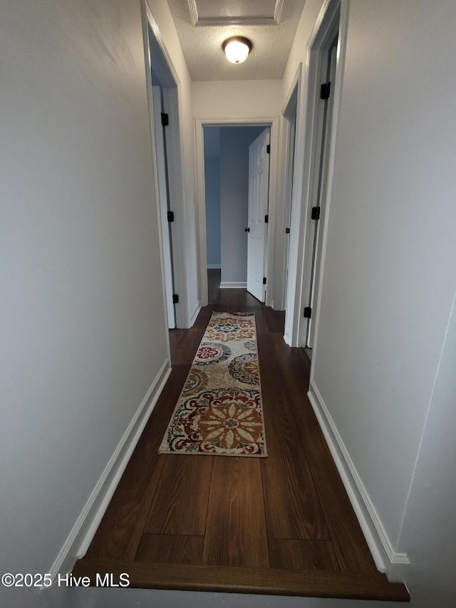 hall with dark wood-type flooring and a textured ceiling