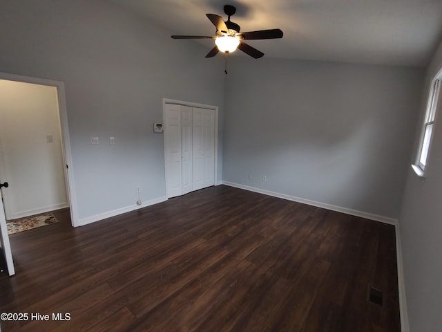 empty room with dark hardwood / wood-style flooring, lofted ceiling, and ceiling fan