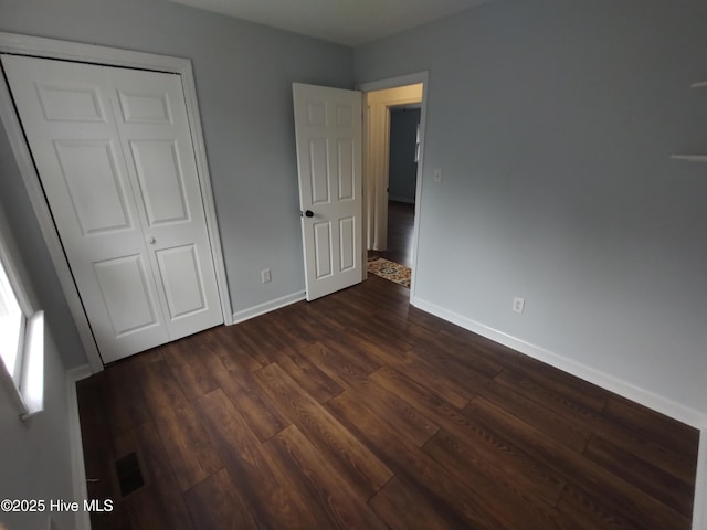 unfurnished bedroom with dark wood-type flooring and a closet