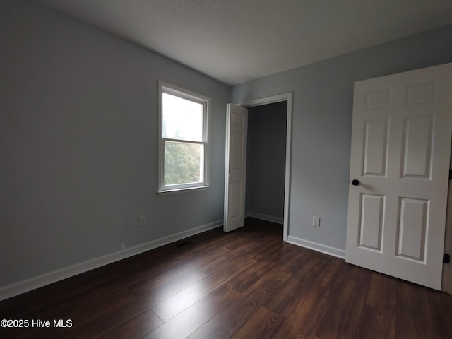 unfurnished bedroom featuring dark hardwood / wood-style flooring and a closet