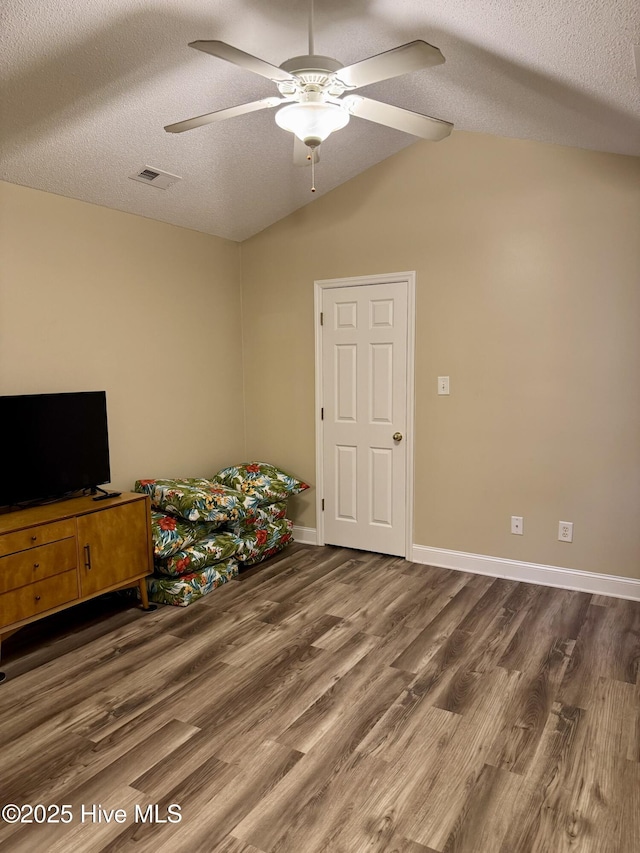 bedroom with ceiling fan, lofted ceiling, dark hardwood / wood-style floors, and a textured ceiling