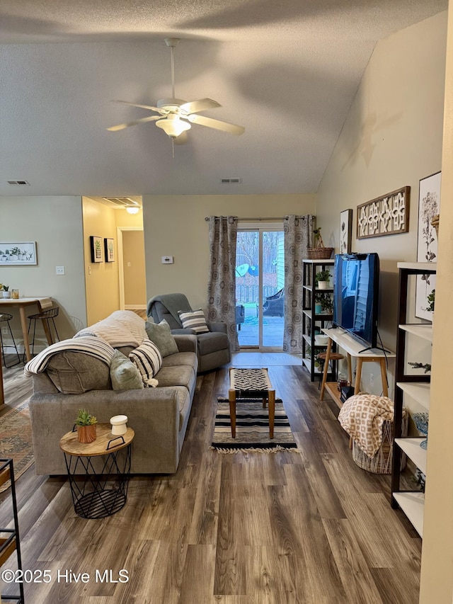 living room featuring ceiling fan, lofted ceiling, dark wood-type flooring, and a textured ceiling