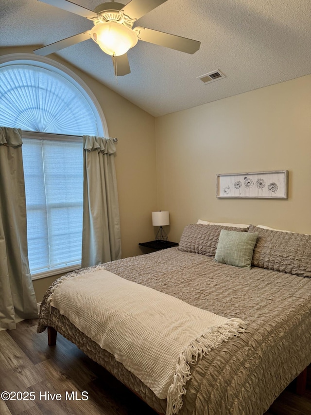 bedroom with multiple windows, dark wood-type flooring, and a textured ceiling