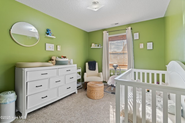 carpeted bedroom with a textured ceiling and a crib