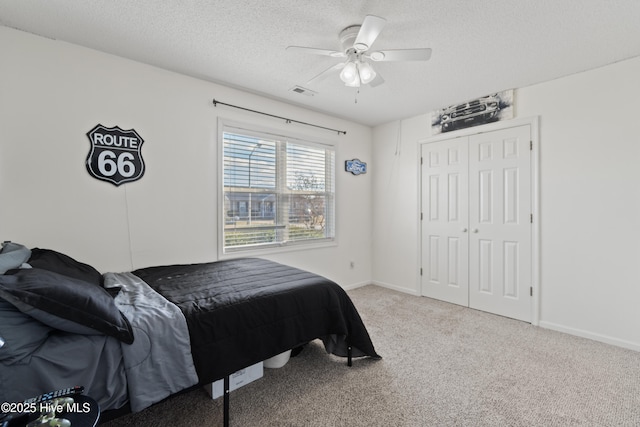 carpeted bedroom with ceiling fan, a closet, and a textured ceiling