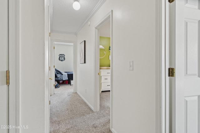 corridor with ornamental molding, light colored carpet, and a textured ceiling