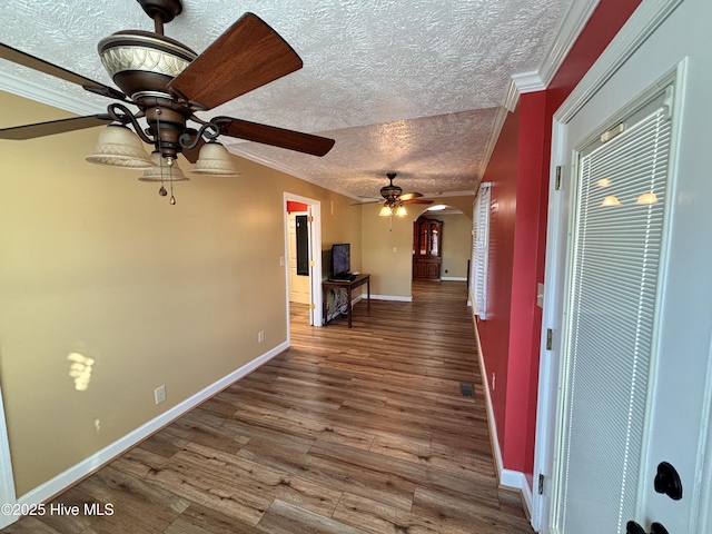 corridor featuring ornamental molding, wood-type flooring, and a textured ceiling